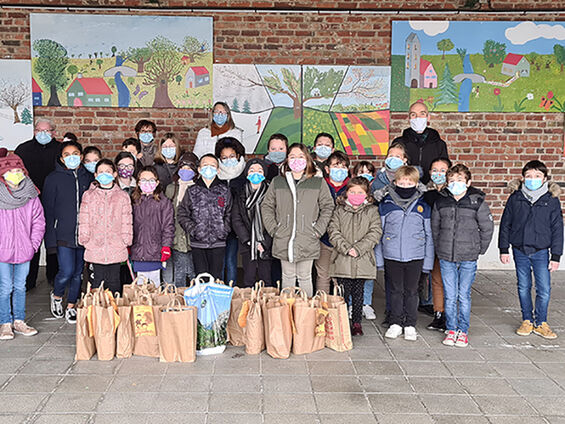 Elèves, professeurs, bénévoles, administrateurs du CCAS et élu(e)s dans la cour de l'école Victor Hugo posant devant la collecte de denrées alimentaires.