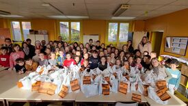 Les élèves de l'école Jules Ferry avec leurs professeurs et des élu(e)s dans une classe de l'école avec les sachets récoltés.