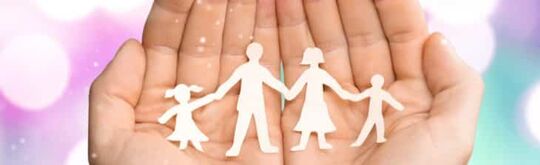 Photographie mains ouvertes jointes tenant dans son creux une famille découpée dans du papier blanc.