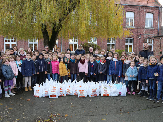 Elèves, professeurs, administrateurs du CCAS et élu(e)s dans la cour de l'école Jules Ferry posant devant la collecte de denrées alimentaires de l'école.