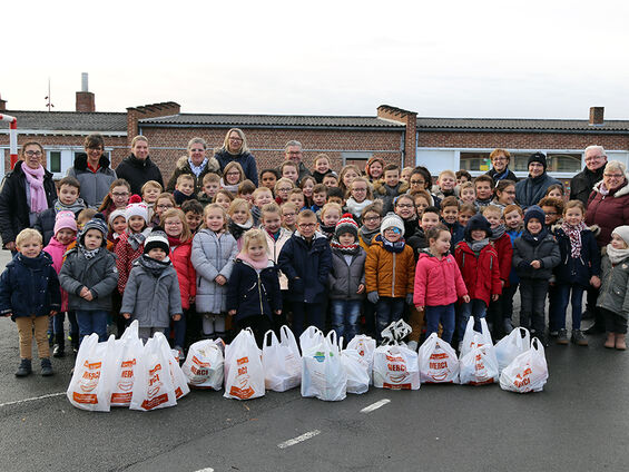 Elèves, professeurs, administrateurs du CCAS et élu(e)s dans la cour de l'école Victor Hugo posant devant la collecte de denrées alimentaires de l'école.
