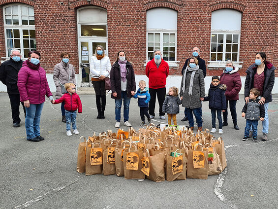 Elèves, professeurs, administrateurs du CCAS et élu(e)s dans la cour de l'école maternelle Suzanne Lanoy posant devant la collecte de denrées alimentaires.